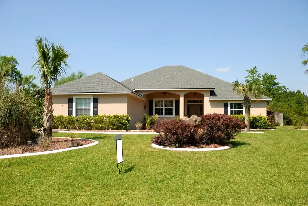 Single-story stucco home with palm trees and a green lawn